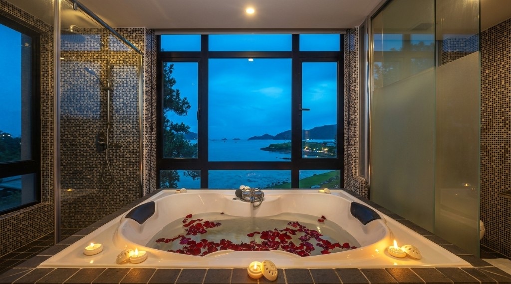 Corner jacuzzi with rose petals and candles facing a dusk sea view