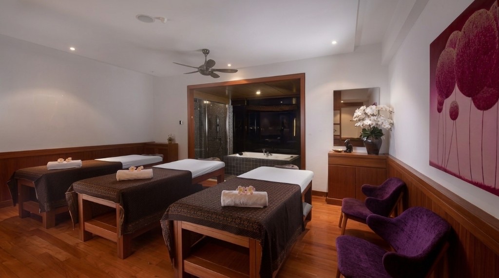 Four spa massage beds in a timber room with purple chairs